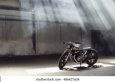 Vintage motorcycle standing in a dark building in the rays of sunlight. Side view