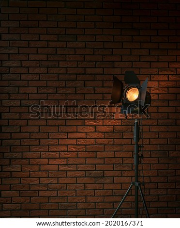 Vintage movie set spotlight lamp with fresnel lens and barndoors in front of red brick wall good as background for production, and moviemaking company