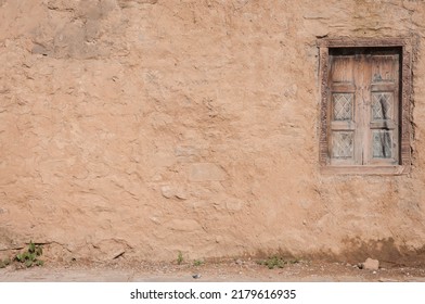 Vintage mud wall with an old wooden window from a village