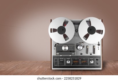 Vintage Music and sound - Retro reel to reel tapes recorder on a wooden table and a brown background.