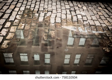 Vintage New York City cobblestone street with puddle and building reflection