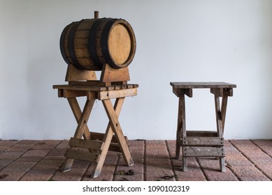 Vintage Oak Wine Barrel Standing On A Wooden Stool Near The Folding Chair. Side View