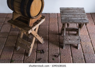 Vintage Oak Wine Barrel Standing On A Wooden Stool Near The Folding Chair. Side View