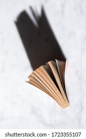 Vintage Old Book Standing On A Table Lit By Natural Light Casting A Shadow