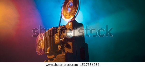Vintage old fashioned projector in\
a dark room projecting a film, cinematography\
concept