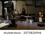 Vintage old microscope on table for science background. Medicine, alchemy, pharmacist. glass jars, flasks and tools, Selective focus.