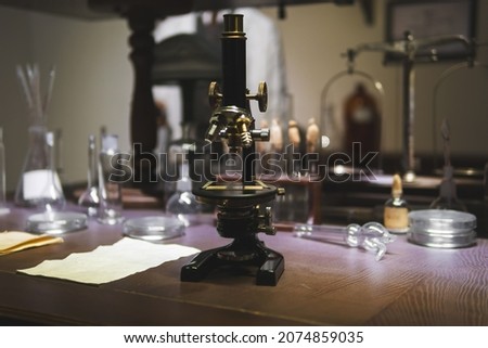 Vintage old microscope on table for science background. Medicine, alchemy, pharmacist. glass jars, flasks and tools, Selective focus.