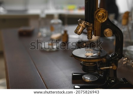 Vintage old microscope on table for science background. Medicine, alchemy, pharmacist. glass jars, flasks and tools, Selective focus.