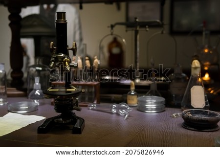 Vintage old microscope on table for science background. Medicine, alchemy, pharmacist. glass jars, flasks and tools, Selective focus.