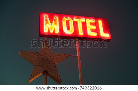 vintage old motel sign glowing in the night sky, vibrant vintage colours 