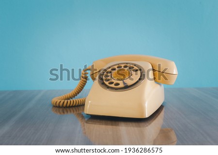 Vintage old phone on the table in front of sky blue background.