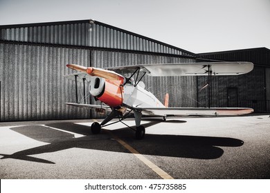 Vintage old plane in front of the hangar. Shadow on the ground.