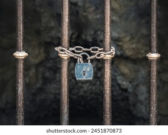 Vintage old rusty padlock with chains on an iron barred gate, dark background - Powered by Shutterstock