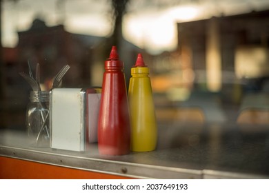 Vintage, old timey restaurant interior with ketchup and mustard sauce bottle contrasted with window reflection of modern street life. 