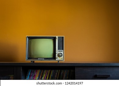 Vintage Old TV On Wooden Table In Room With Yellow Concrete Wall Background