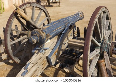 Vintage Old Wild West Wooden Canon In Mexican Hacienda Courtyard Supported By Rusted Metal Wheels