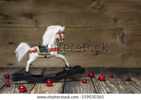 Vintage - old wooden rocking horse on a wooden old board for a christmas card with red balls - classic decoration