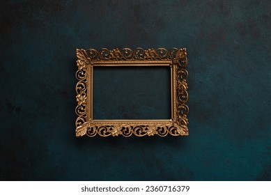 Vintage openwork bronze metal frame on a blue wall background, empty picture frame mockup