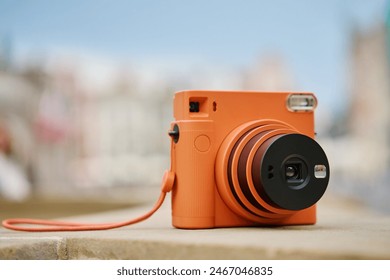 Vintage Orange Instant Camera in city with cloudy sky. Travel shooting equipment - Powered by Shutterstock