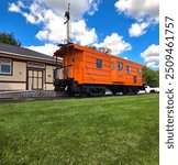 Vintage Orange Milwaukee Road Rail Car on Track at Old Railway Station with Sunny Day and Fluffy Clouds