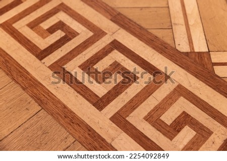 Vintage parquet made of of various wood planks with geometric ornament known as the Greek Key or Meander. Background photo texture