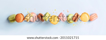 Vintage pastel colored French macaroons or macarons in motion falling on light blue background.Food banner Macaron Sweets