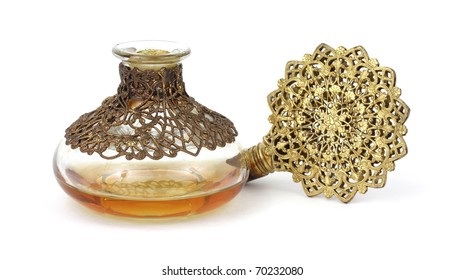 Vintage perfume bottle with gold filigree stopper on it's side with amber colored liquid.