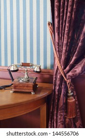Vintage phone on table near wall with striped wallpaper and curtain with cord brush. - Shutterstock ID 144556706