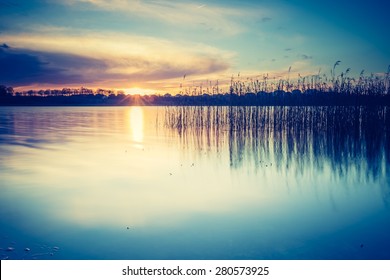 Vintage photo of beautiful sunset over calm lake. Mazury lake district landscape.