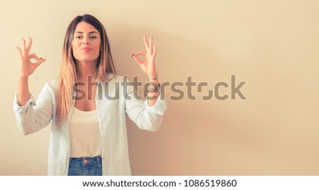 Vintage photo of a Beautiful woman against wall doing ok sign gesture with both hands expressing meditation and relaxation