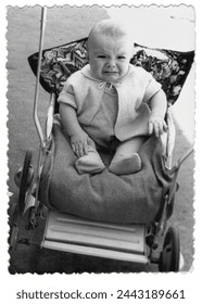 Vintage photo of a boy in a stroller. The baby is crying. Photo from 1961.