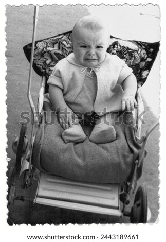 Vintage photo of a boy in a stroller. The baby is crying. Photo from 1961.