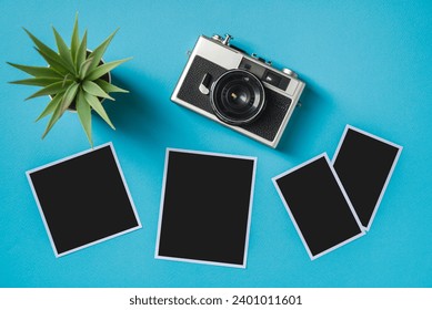 Vintage photo camera and empty photo frames on blue background. Travel moment concept