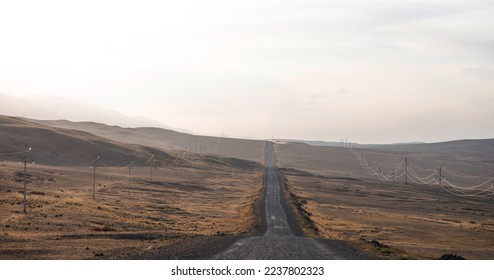 Vintage photo of a country road. Empty road through the desolate hilly area. Cloudy sky and horizon in a haze. Concept landscape. Rural scene. - Shutterstock ID 2237802323