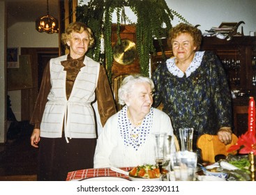 Vintage photo of elderly woman and her adult daughters during a Christmas dinner, eighties