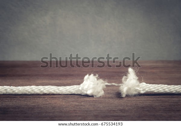 Vintage photo of Rope almost torn apart ,\
Breaking rope on wooden background with copy space , Tension and\
Risk of breaking\
concept