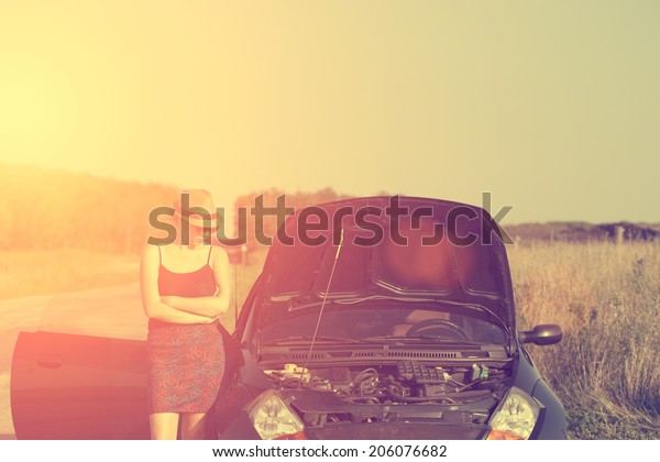 Vintage photo of woman with broken down car in\
summer sunset