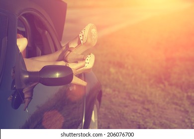 Vintage Photo Of Woman's Legs In High Heel Shoes Out Of Car Windows In Summer Sunset