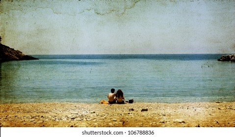 Vintage Photo Of A Young Couple Sitting On The Beach And Looking At Sea