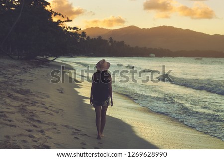 Vintage photo of young girl traveler in vacation. Traveler walking on tropical beach in vacation. Girl in vacation walking on beach in sunset. Traveler. Vacations. Vintage.