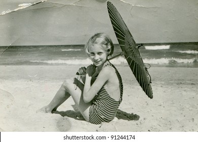 Vintage photo of young girl with umbrella on beach (fifties)
