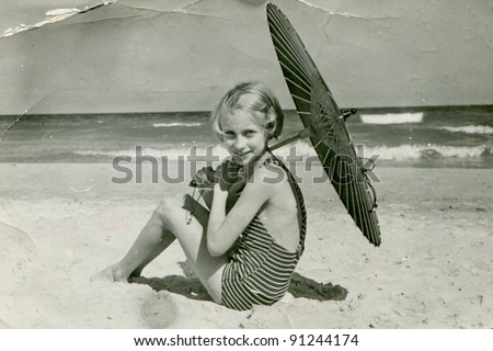 Vintage photo of young girl with umbrella on beach (fifties)