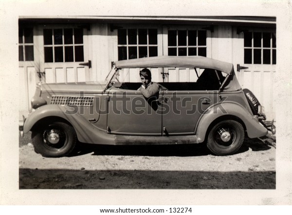 Vintage photo\
of a young man in a car. Circa\
1937