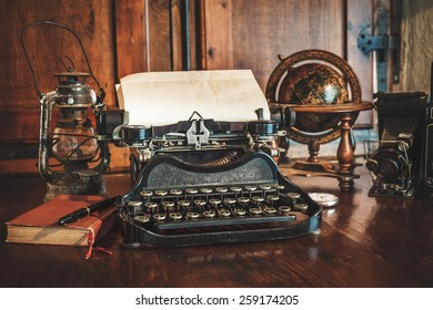vintage photography still life with typewriter, folding camera, globe map and book on a wood table.