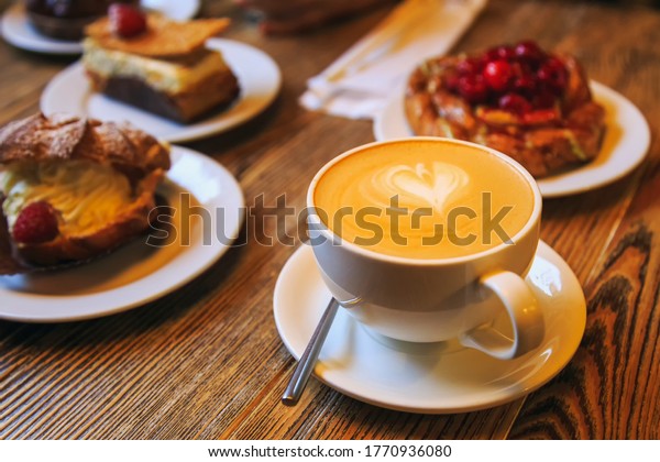 Vintage\
photography style of Coffee and desserts pastry, puffs, tarts,\
cakes on wooden table top, selected\
focus.