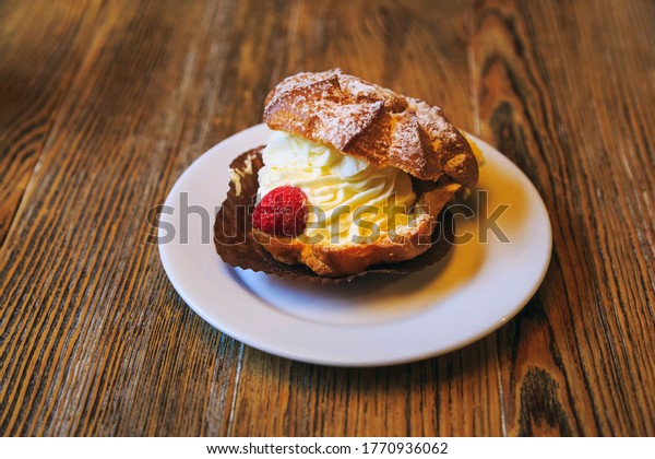 Vintage photography style of cream pastry\
puff dessert on wooden table top, selected\
focus.