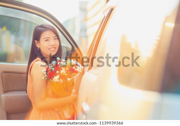 Vintage Photography\
style of Pretty Asian woman portrait with roses flower bouquet in\
sun light background.