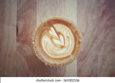 Vintage Picture Cup Of Coffee With Two Hearts Milk Foam Pattern And Peanut Butter Crumble Coated Cup Mouth On Wooden Background.