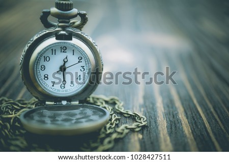 Vintage pocket watch on old wooden texture using as background long time ago, wallpaper concept.