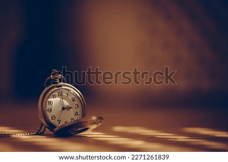 vintage pocket watch in shade lit by sun rays on blurred background